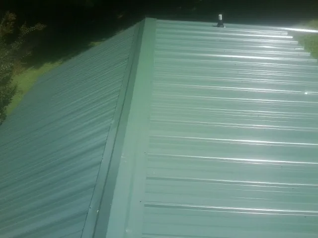 New green metal panels meeting at the ridge of a roof — Flat Roof Repair work by our crew in Brantingham