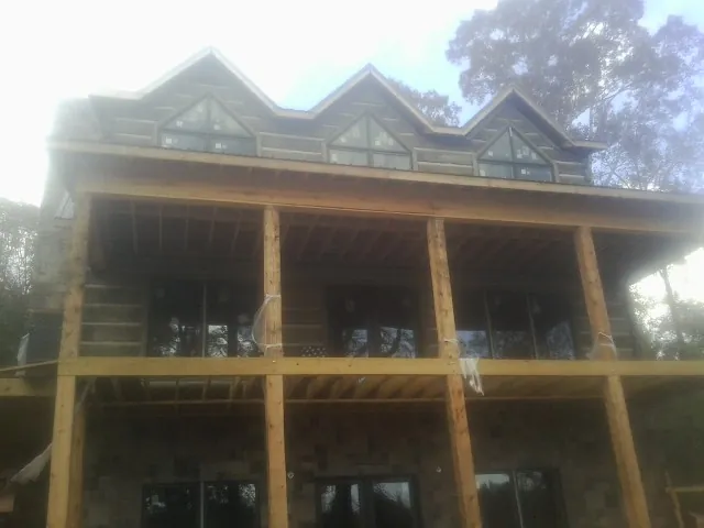 Dormers and porch framing on a large log home under construction — Roof Coating work by our crew in Brantingham