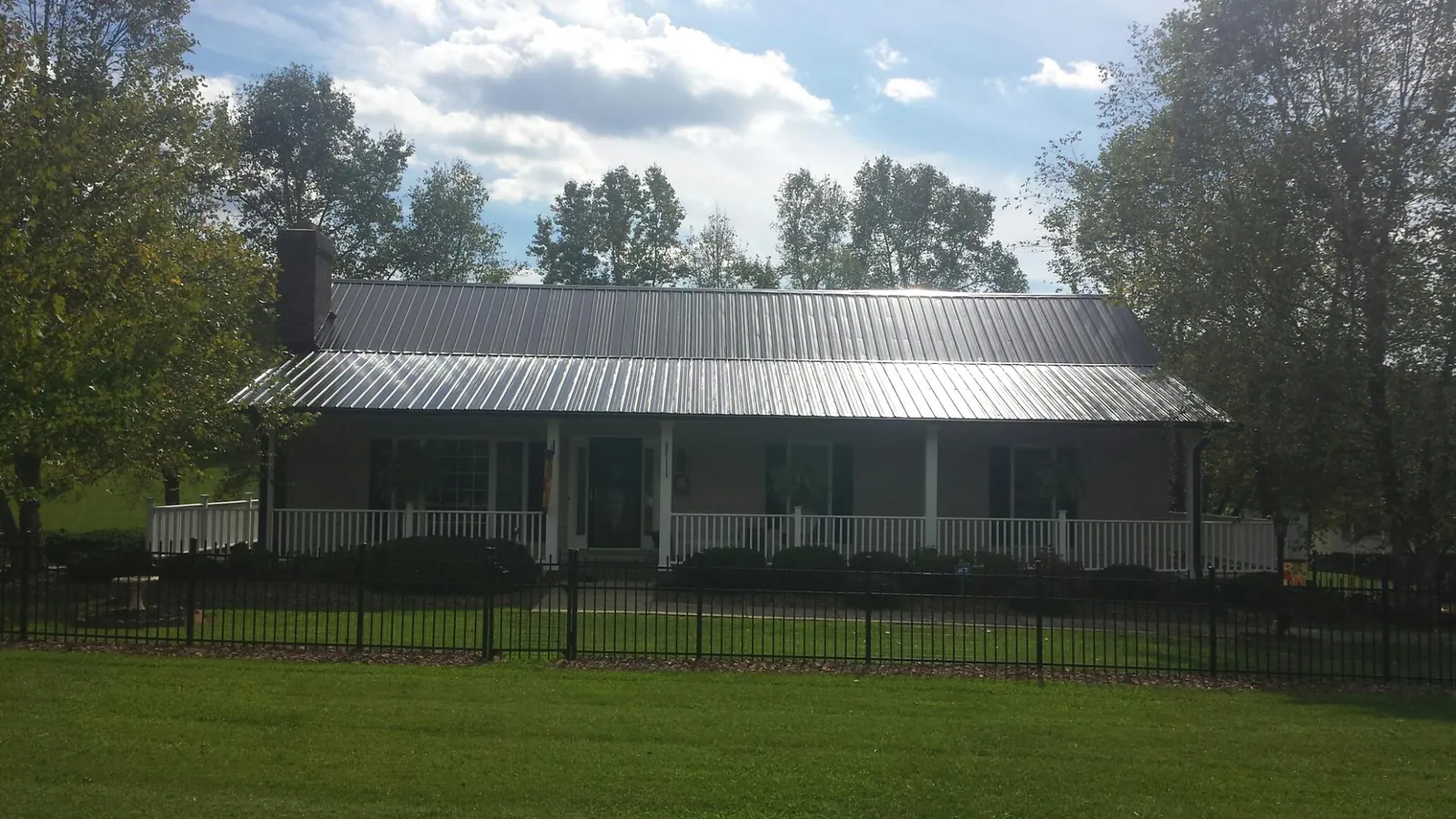 Gray metal roof on a brick ranch with a full width front porch — Gutter Guard Installation work by our crew in Brantingham